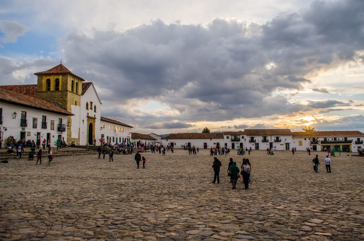 Atardecer con nubes dramáticas sobre la plaza mayor de Villa de Leyva y sus visitantes