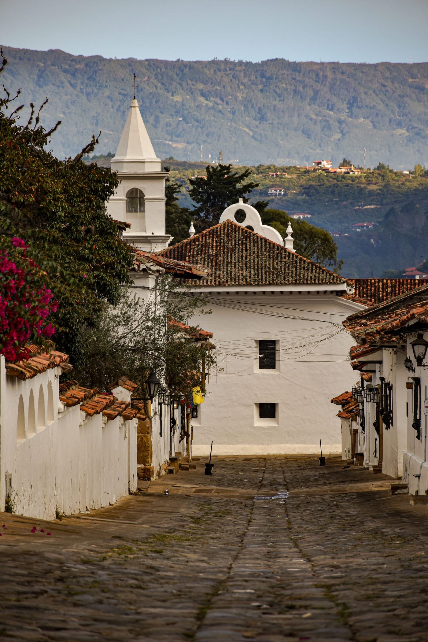 Calle empedrada de Villa de Leyva con vista a la torre de una iglesia colonial