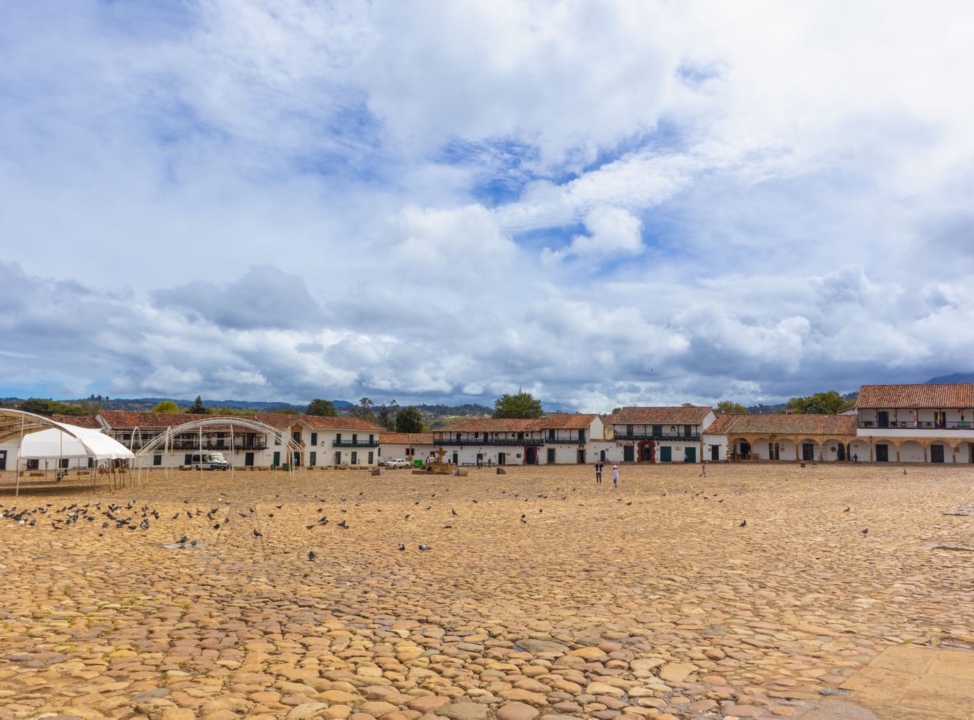 Vista panorámica de la plaza mayor de Villa de Leyva con palomas y las casas coloniales al fondo