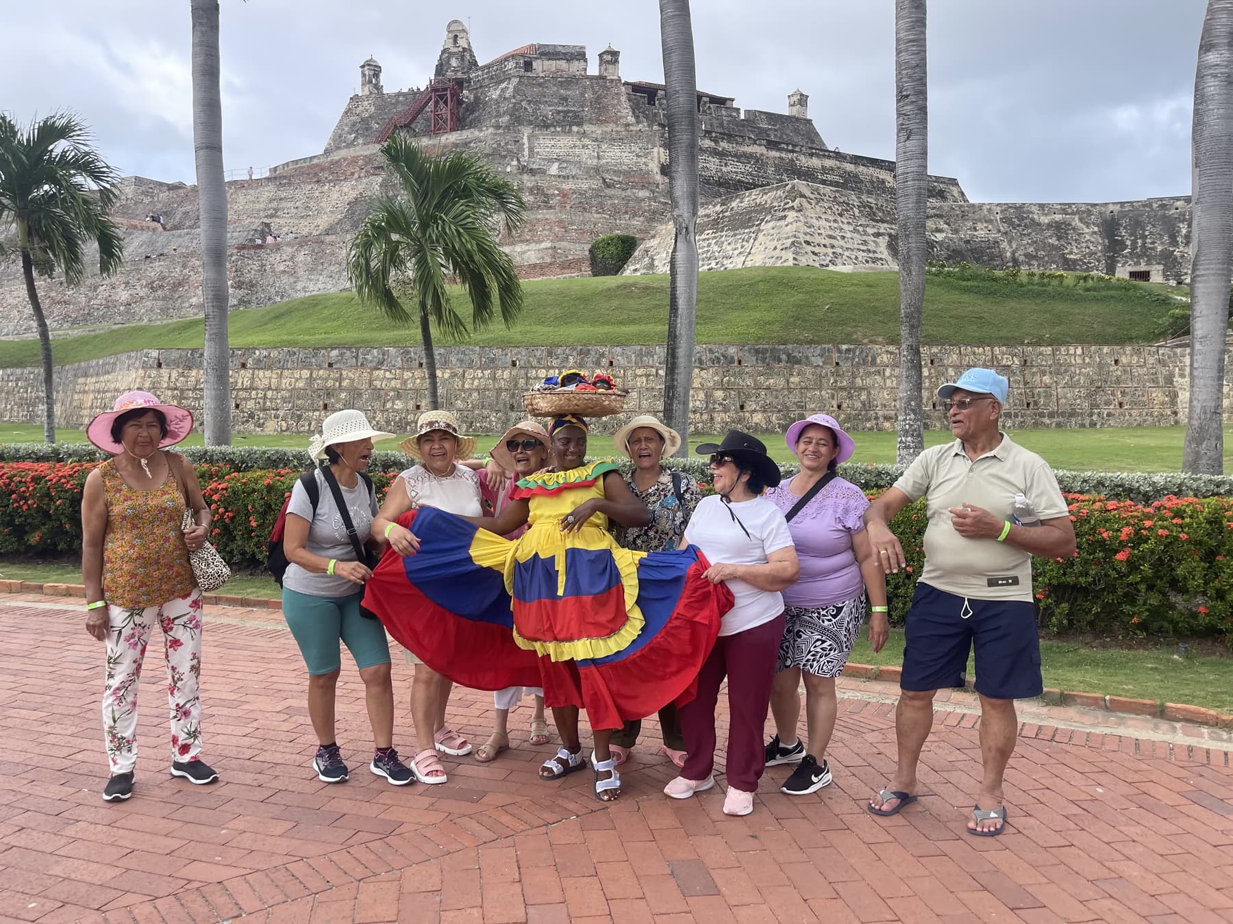 Grupo de turistas posando con la bandera de Colombia frente al Castillo San Felipe de Barajas
