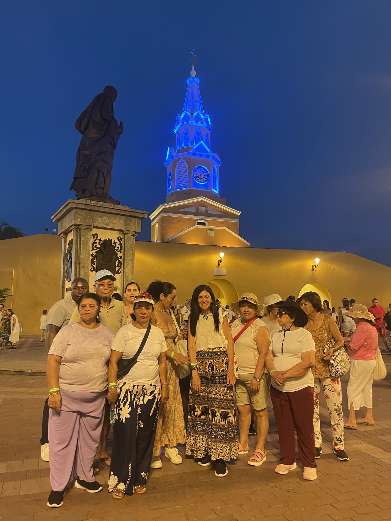 Grupo de turistas reunido en la plaza de la Torre del Reloj de Cartagena iluminada por la noche