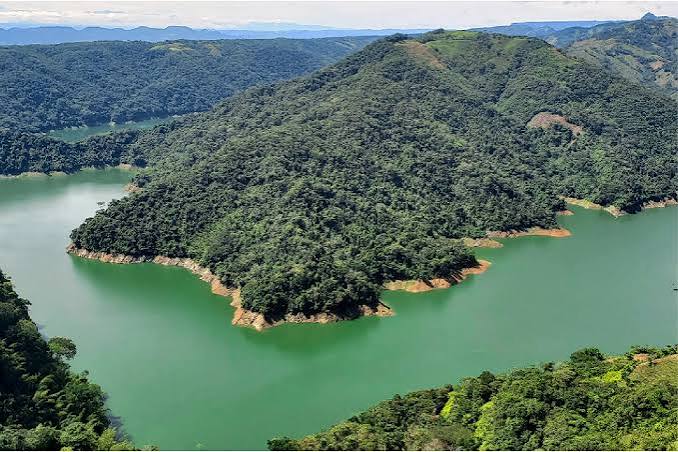 Panorámica del embalse Amaní serpenteando entre colinas verdes bajo un cielo nublado