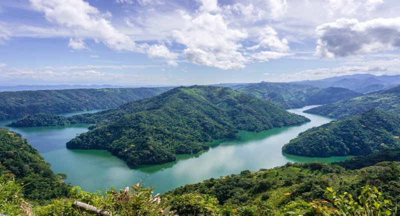 Vista aérea del embalse Amaní de aguas verdes rodeado de montañas boscosas en Norcasia
