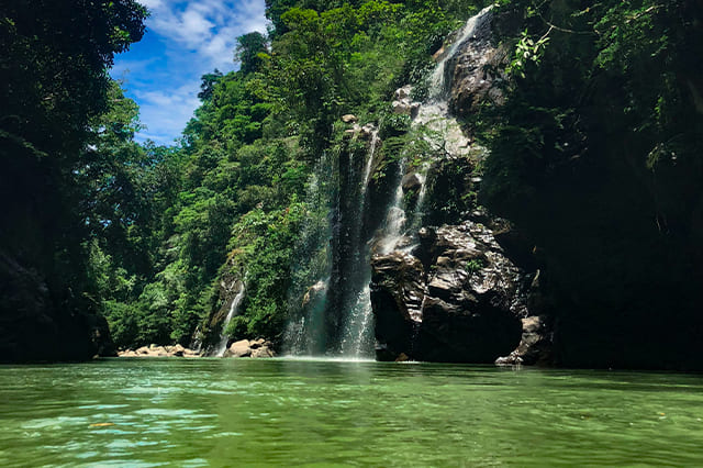 Cascada cayendo en una poza de aguas turquesas rodeada de selva en Norcasia