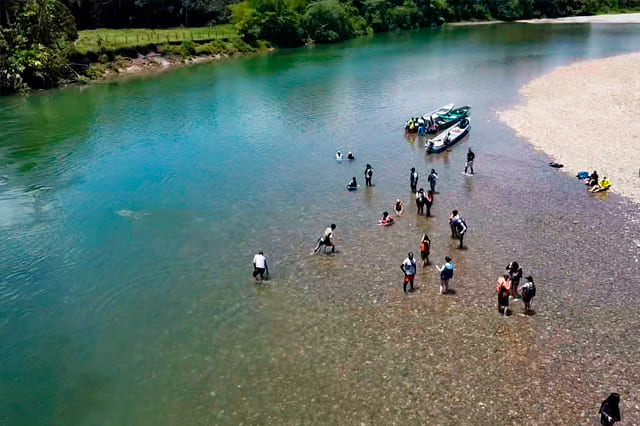 Grupo de turistas y lanchas en una playa de río de aguas cristalinas en Norcasia