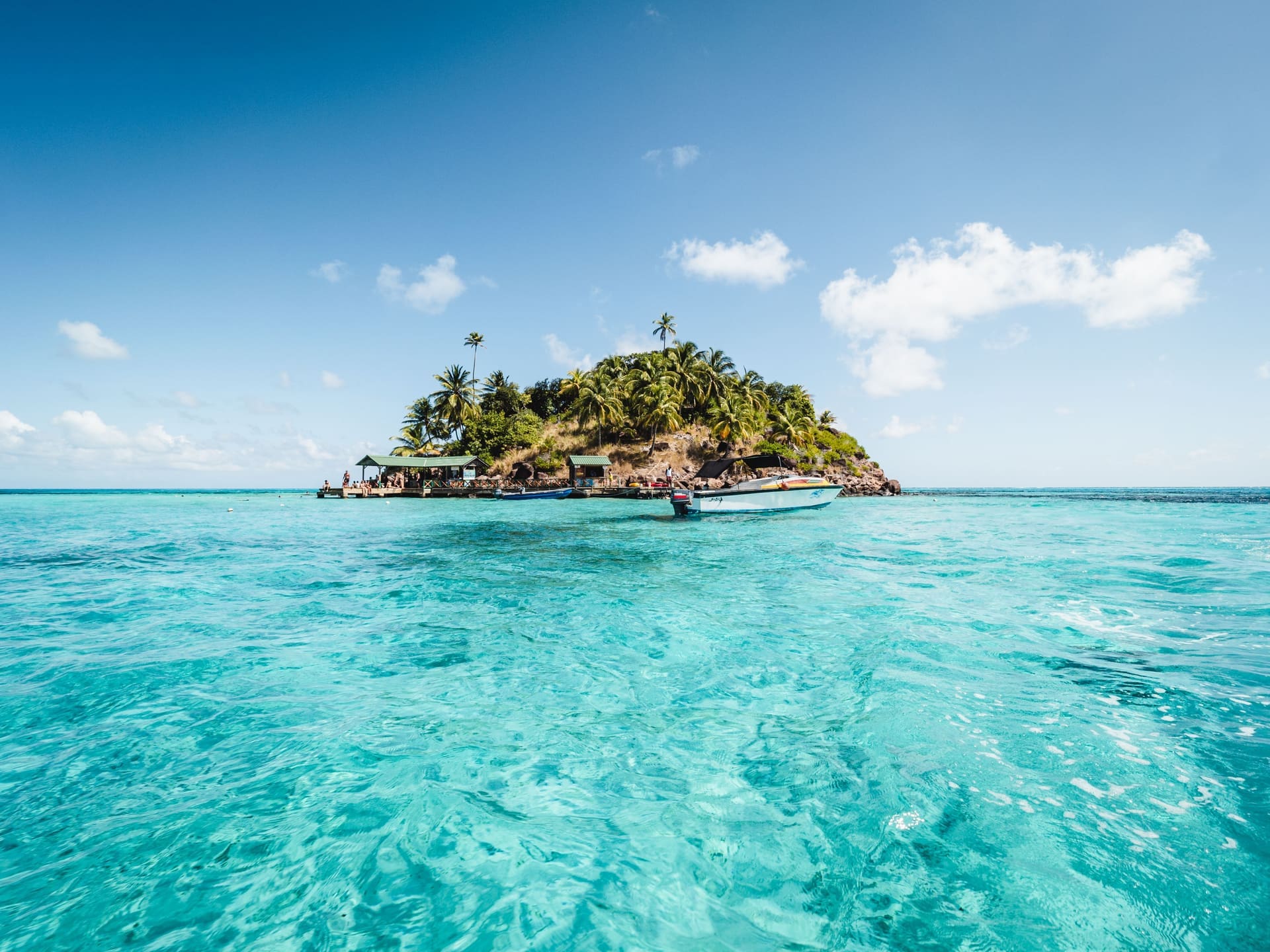 Vista de Johnny Cay desde el mar, islote con palmeras y lanchas turísticas en aguas turquesa