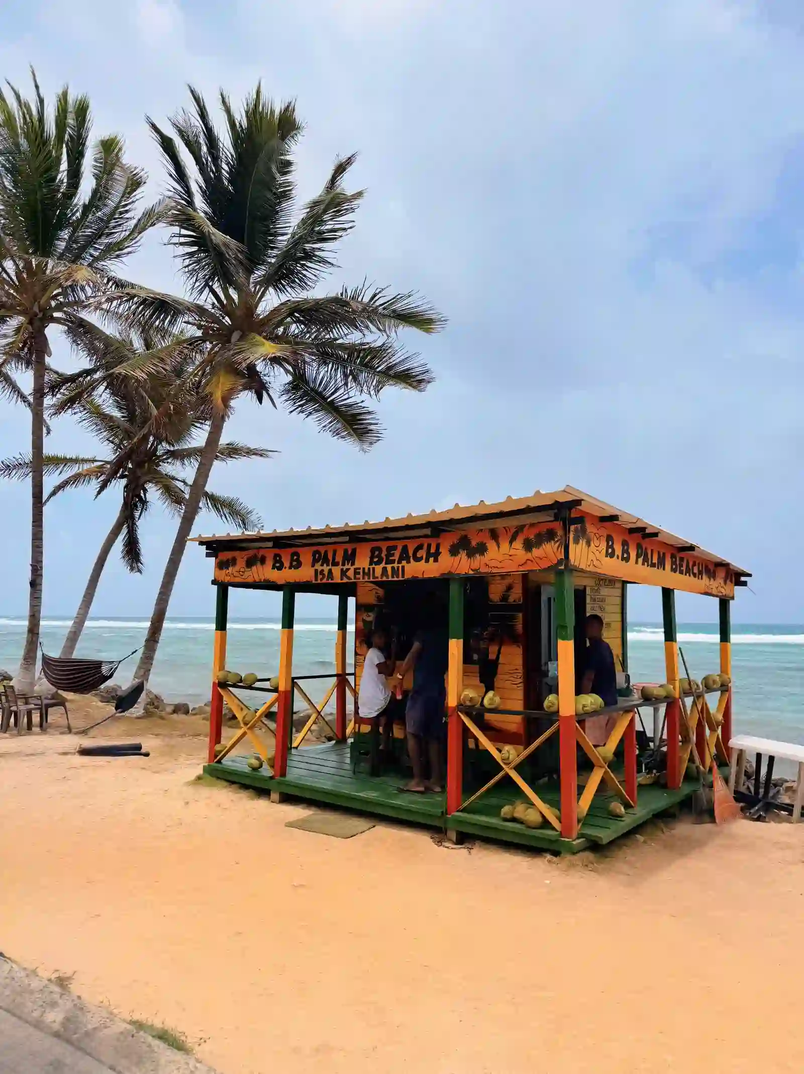 Kiosco B.B. Palm Beach con palmeras y turistas comprando cocos frente al mar en San Andrés