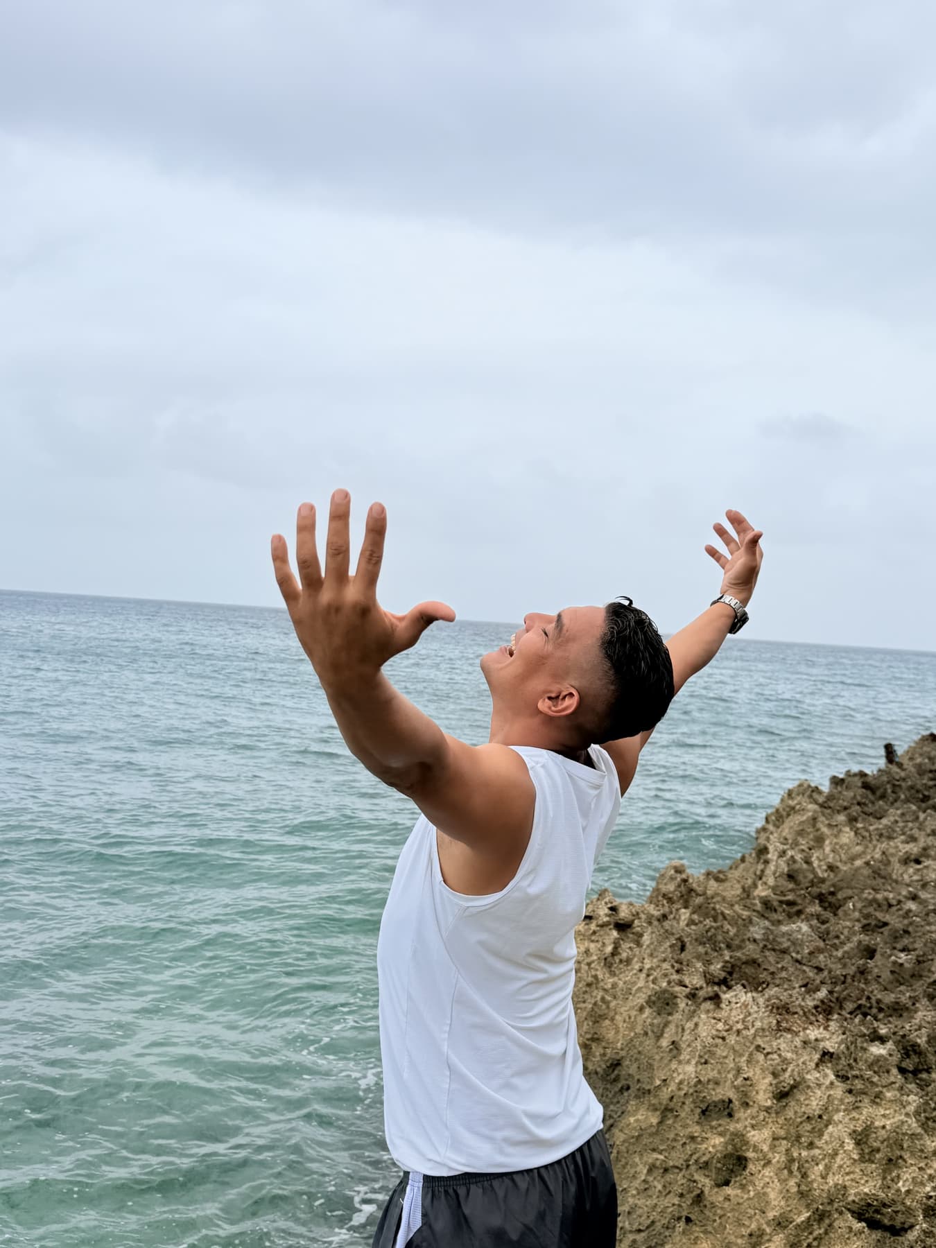 Turista celebrando con los brazos en alto sobre las rocas junto al mar de San Andrés