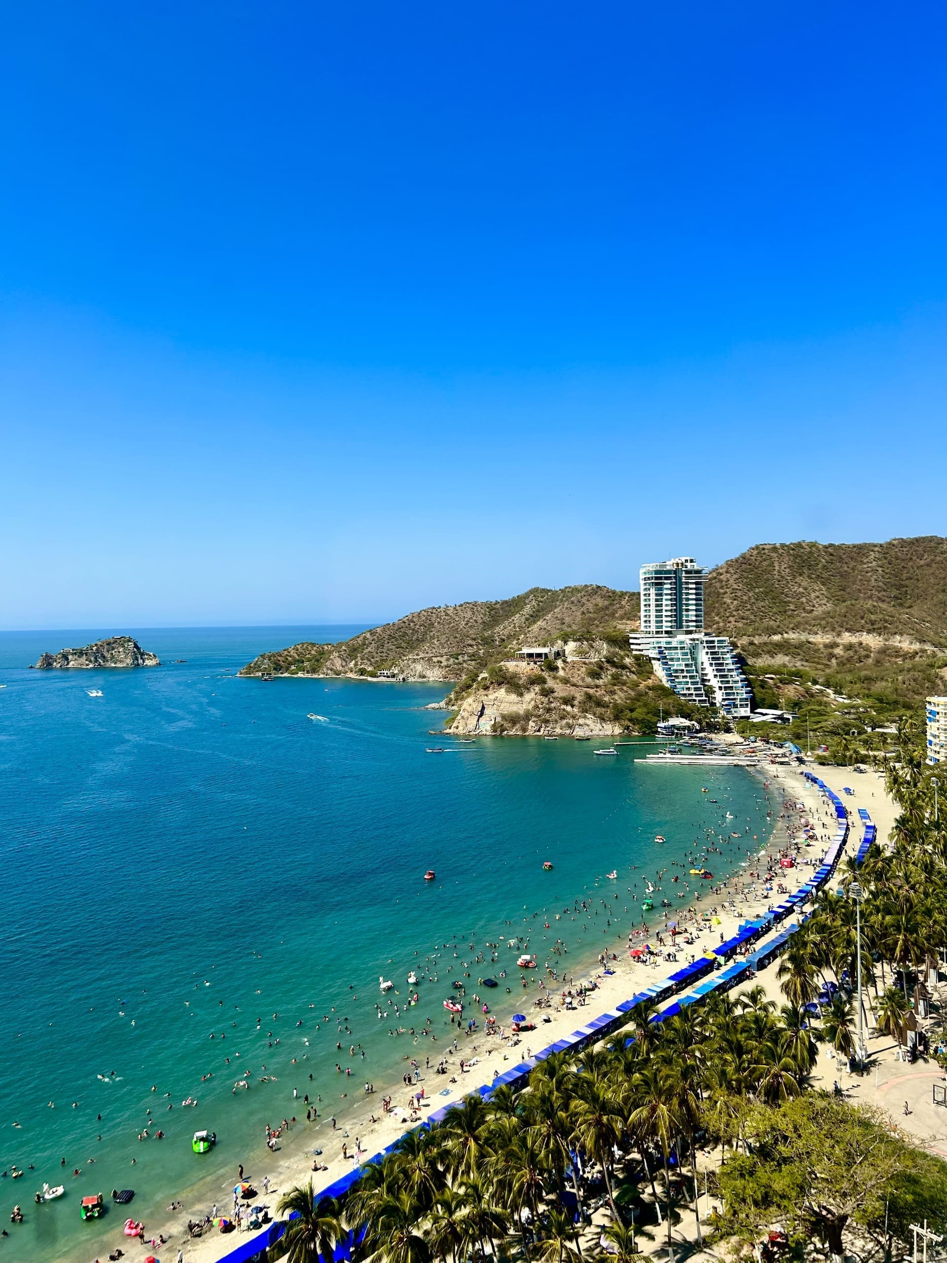 Vista aérea de la bahía de El Rodadero en Santa Marta, con edificios frente al mar y una lancha turística