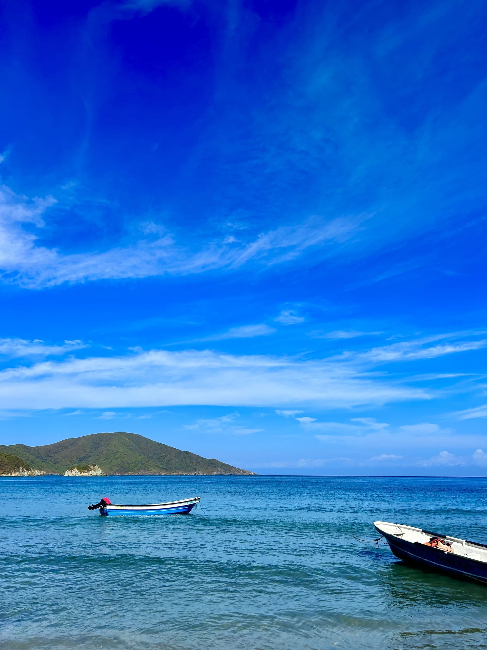 Bahía del Parque Tayrona con una lancha de pescadores y montañas verdes al fondo