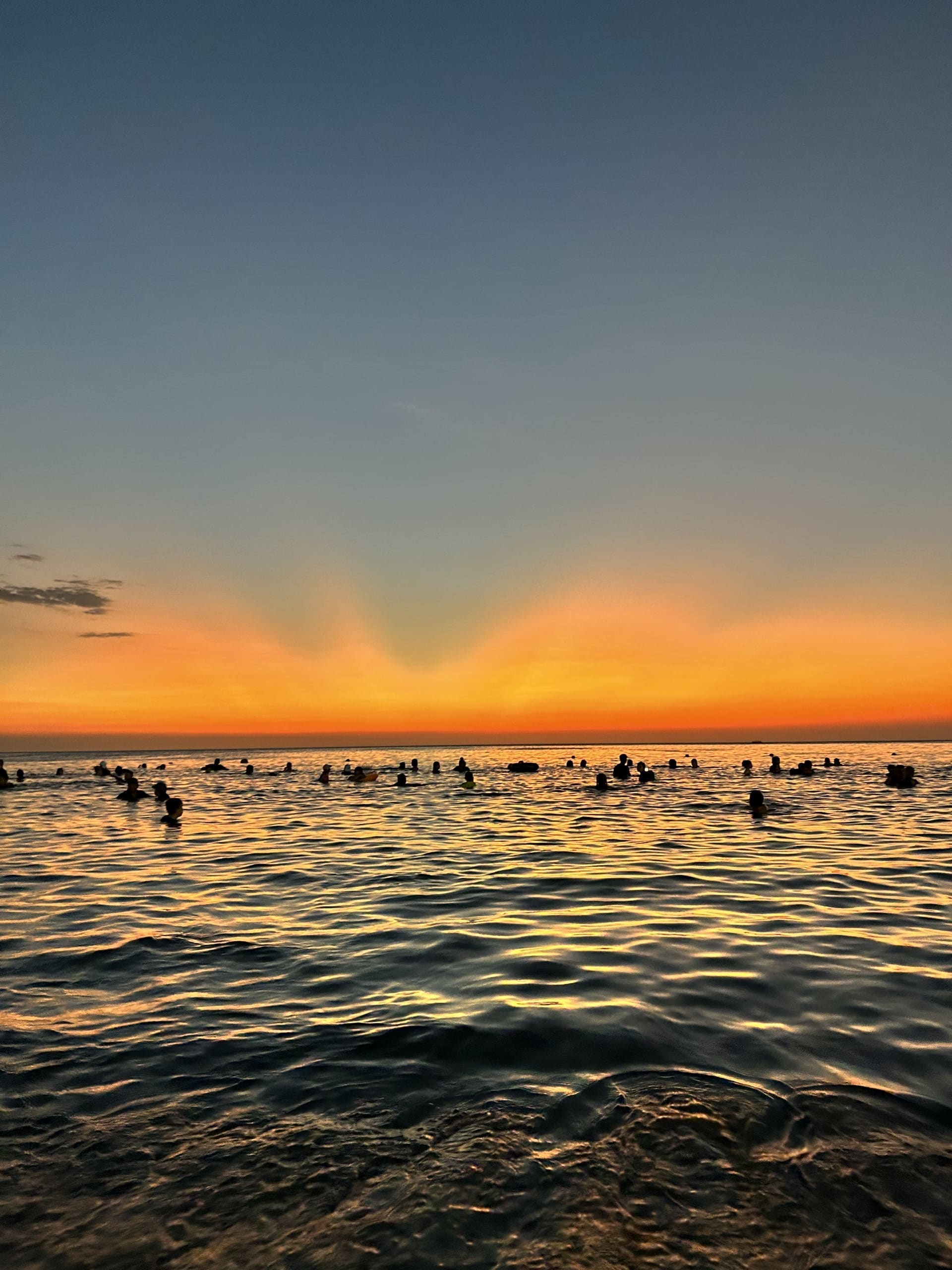 Bañistas disfrutando del mar en Santa Marta durante un atardecer anaranjado