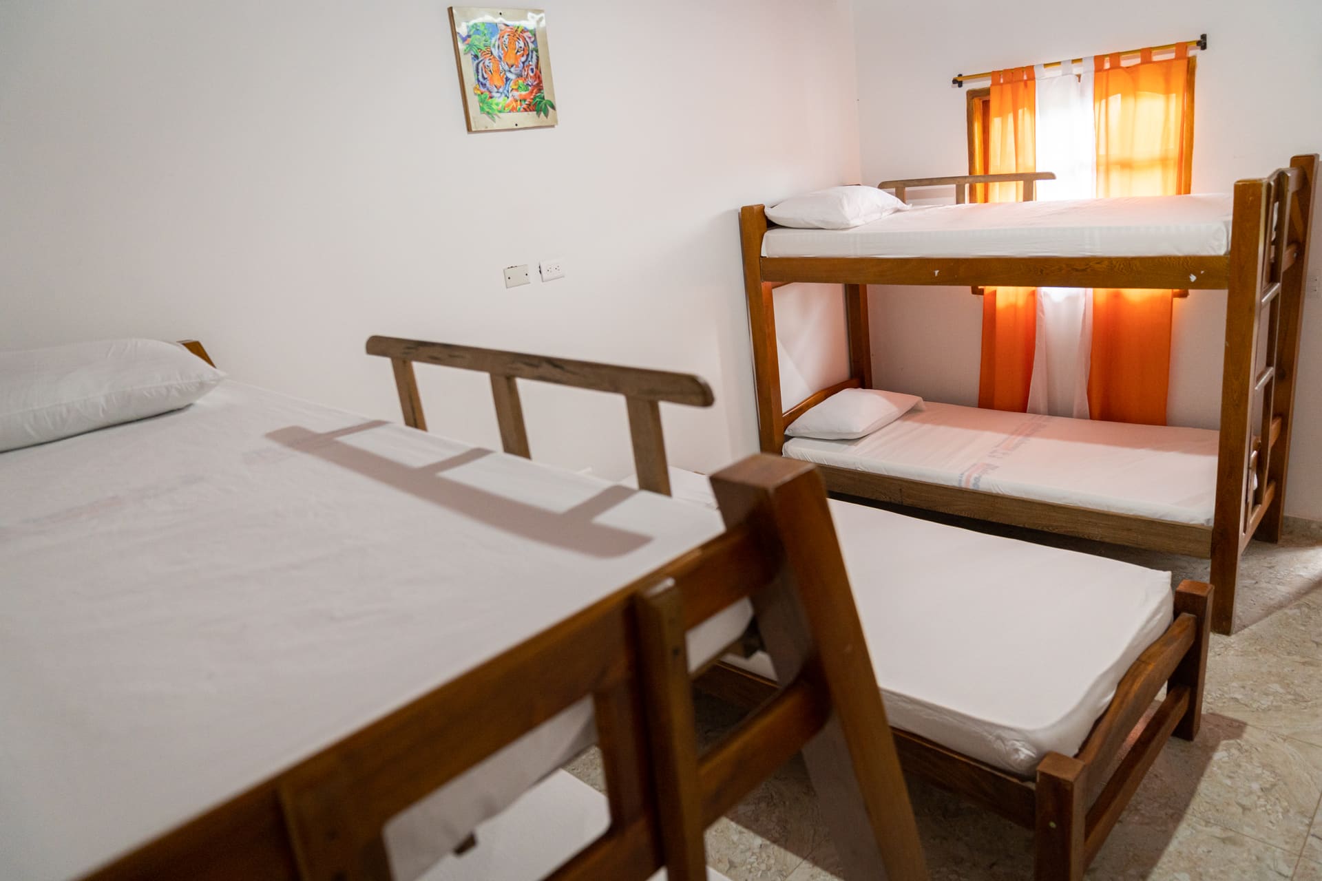 Habitación de Apartahotel Acapulco con cama doble, cama nodriza y litera con cortina naranja