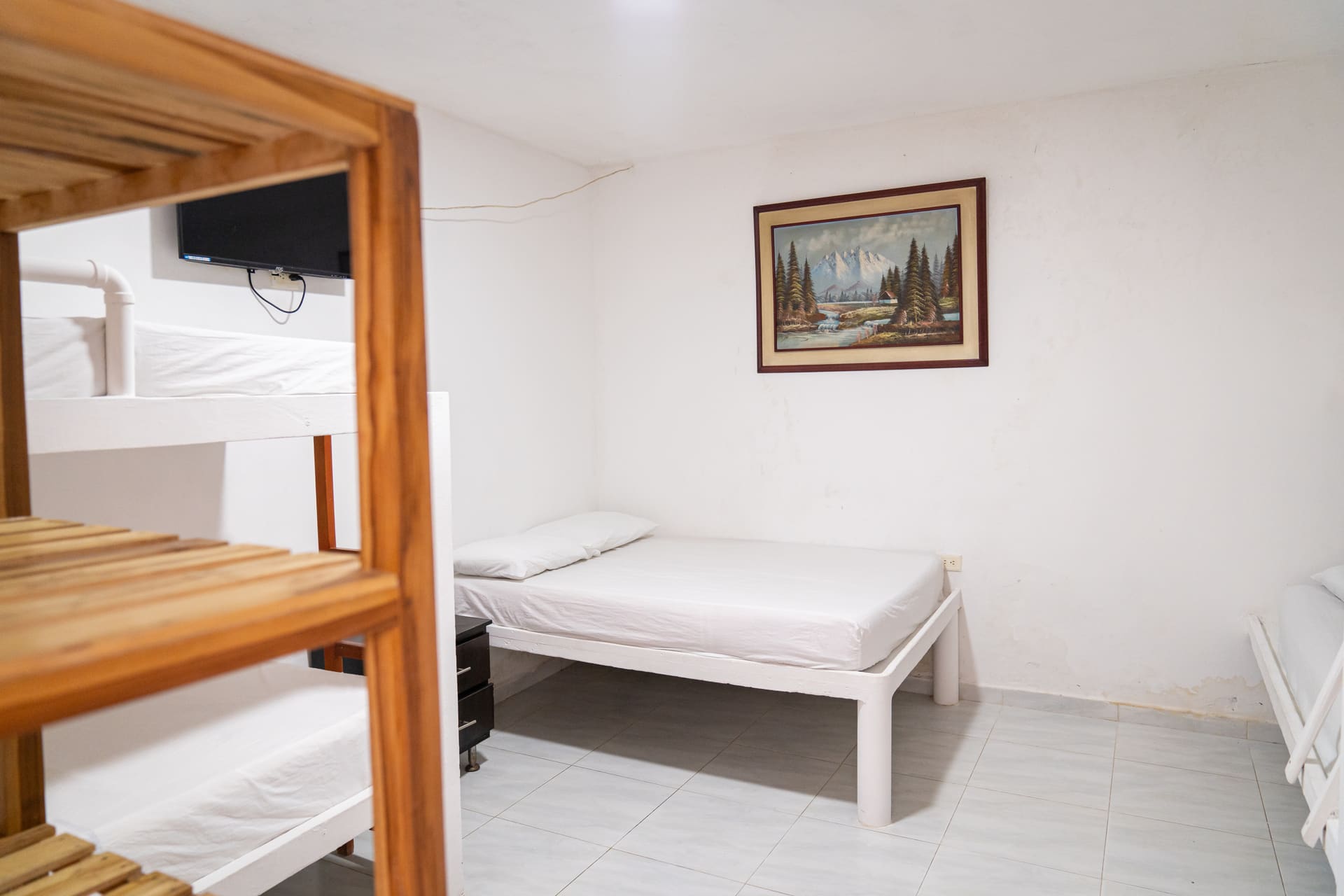 Habitación de Apartahotel Acapulco con litera, televisor y cuadro de paisaje de montaña