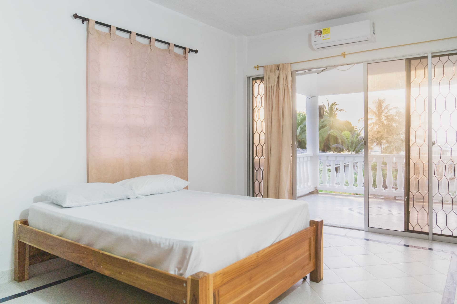 Habitación de Apartahotel Acapulco con balcón, cortina rosada y vista a las palmeras