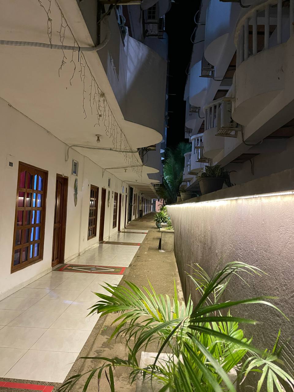 Pasillo exterior de Apartahotel Acapulco iluminado de noche, con vista a las habitaciones
