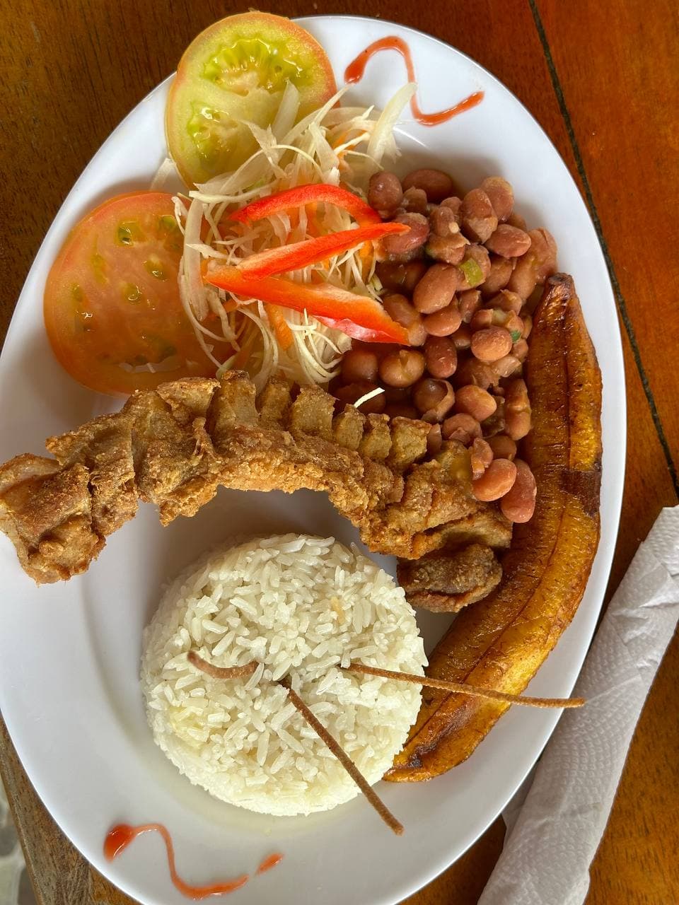 Plato de costillas de cerdo con arroz, plátano maduro y ensalada en Apartahotel Acapulco