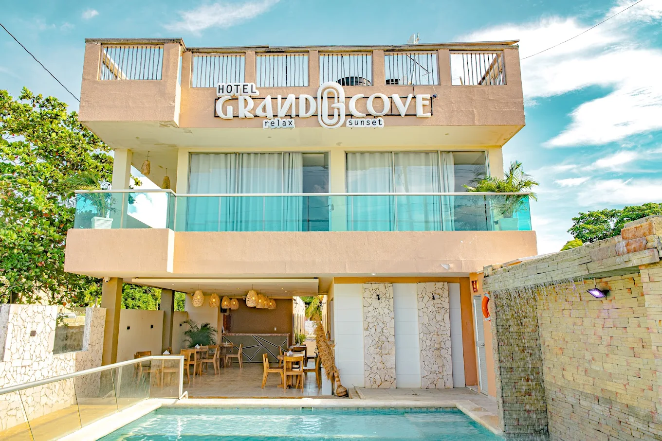 Fachada de Hotel Grand Cove con letrero iluminado y piscina frente al mar en Coveñas