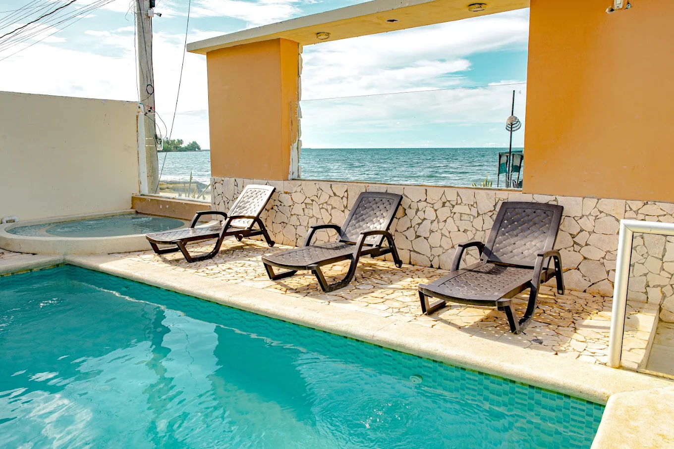 Piscina con jacuzzi de Hotel Grand Cove, con camastros y vista al mar Caribe