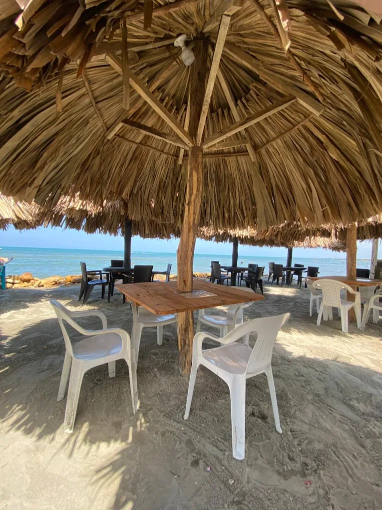 Palapa de paja en la playa de Hotel Grand Cove con mesas y sillas frente al mar