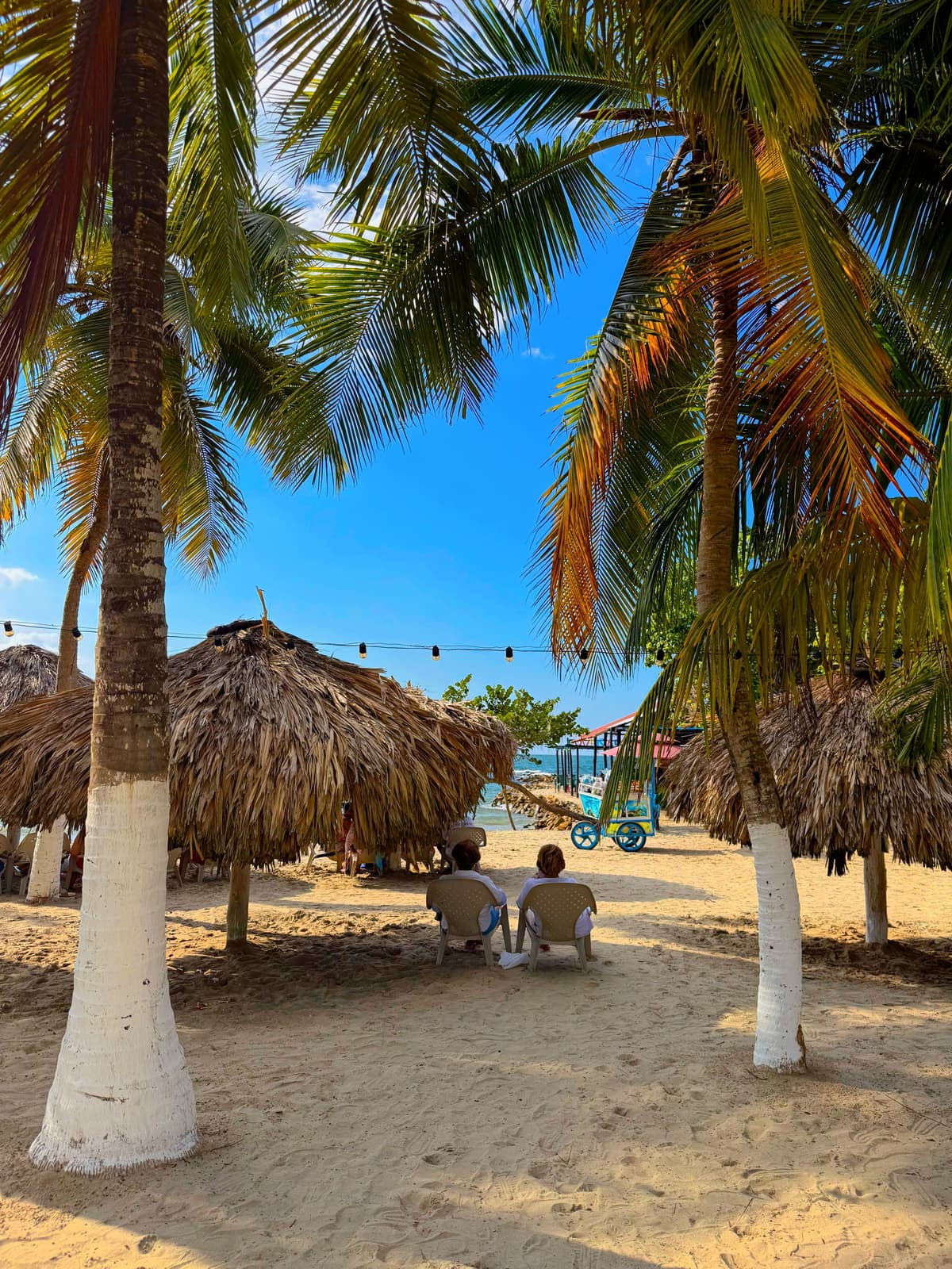 Turistas descansando bajo las palapas de la playa de Hotel Kiimala en Coveñas