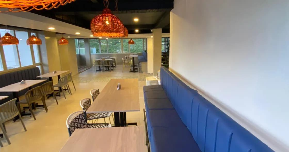 Zona de restaurante de Hotel Vadamar con mesas de madera y lámparas colgantes anaranjadas