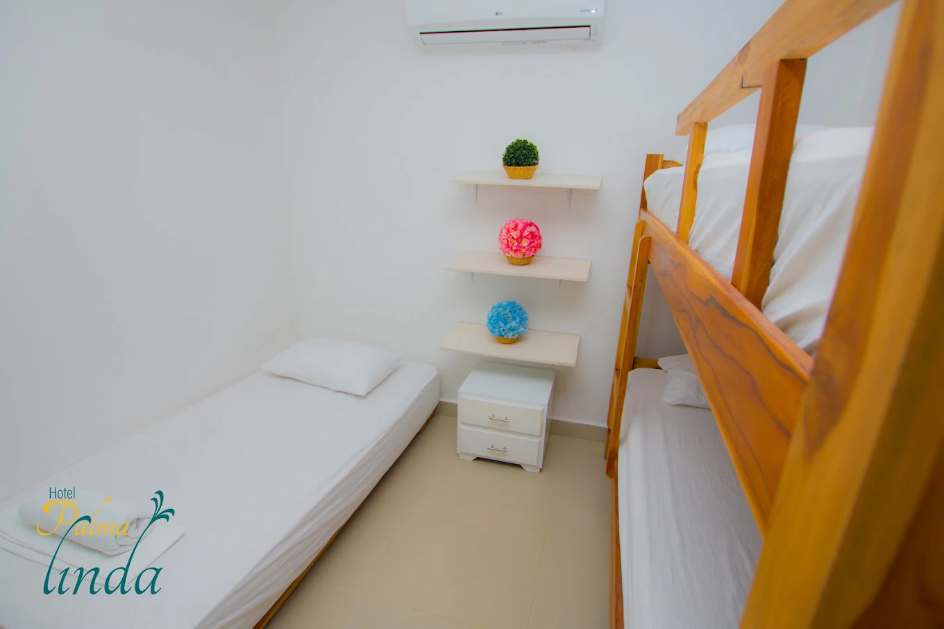 Habitación de Palma Linda con litera y logo del hotel en la pared
