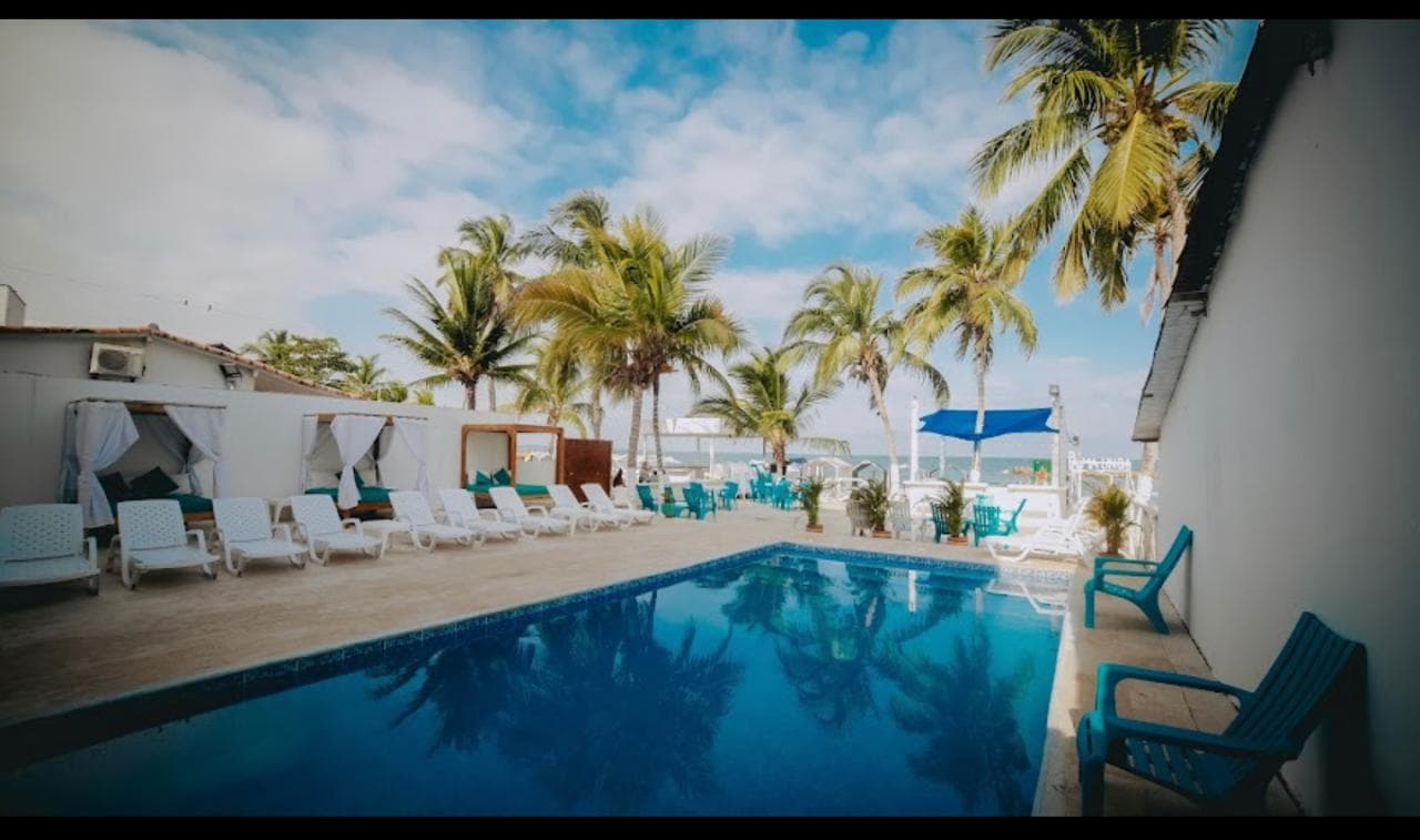 Piscina de Palma Linda rodeada de palmeras y camastros junto al mar