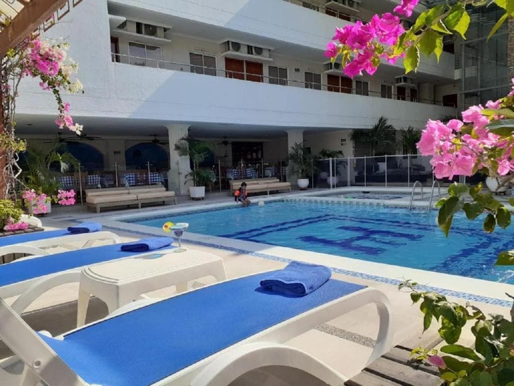 Piscina de Hotel Tayrona Rodadero rodeada de buganvillas, con un niño disfrutando del agua