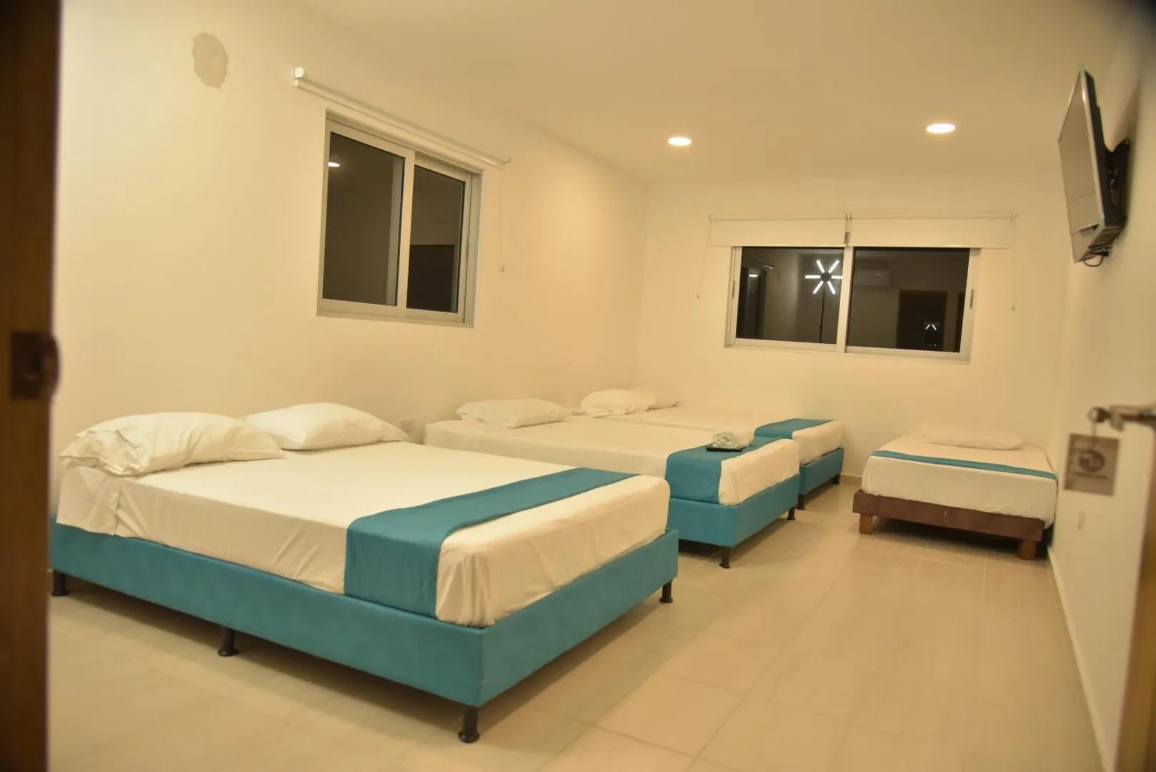 Habitación de cuatro camas en Torre Blanca con televisor y ventanales