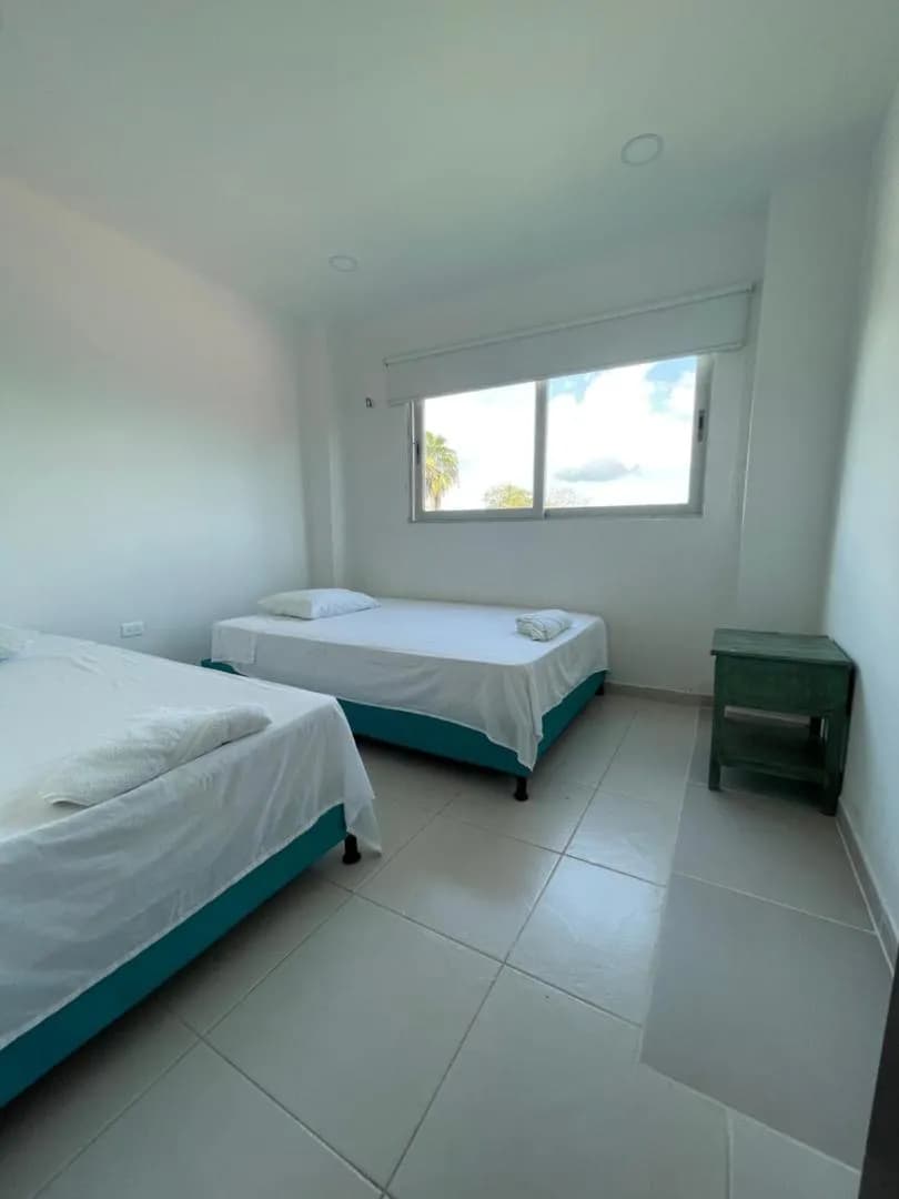 Habitación de Torre Blanca con camas y mesa de noche en tono turquesa