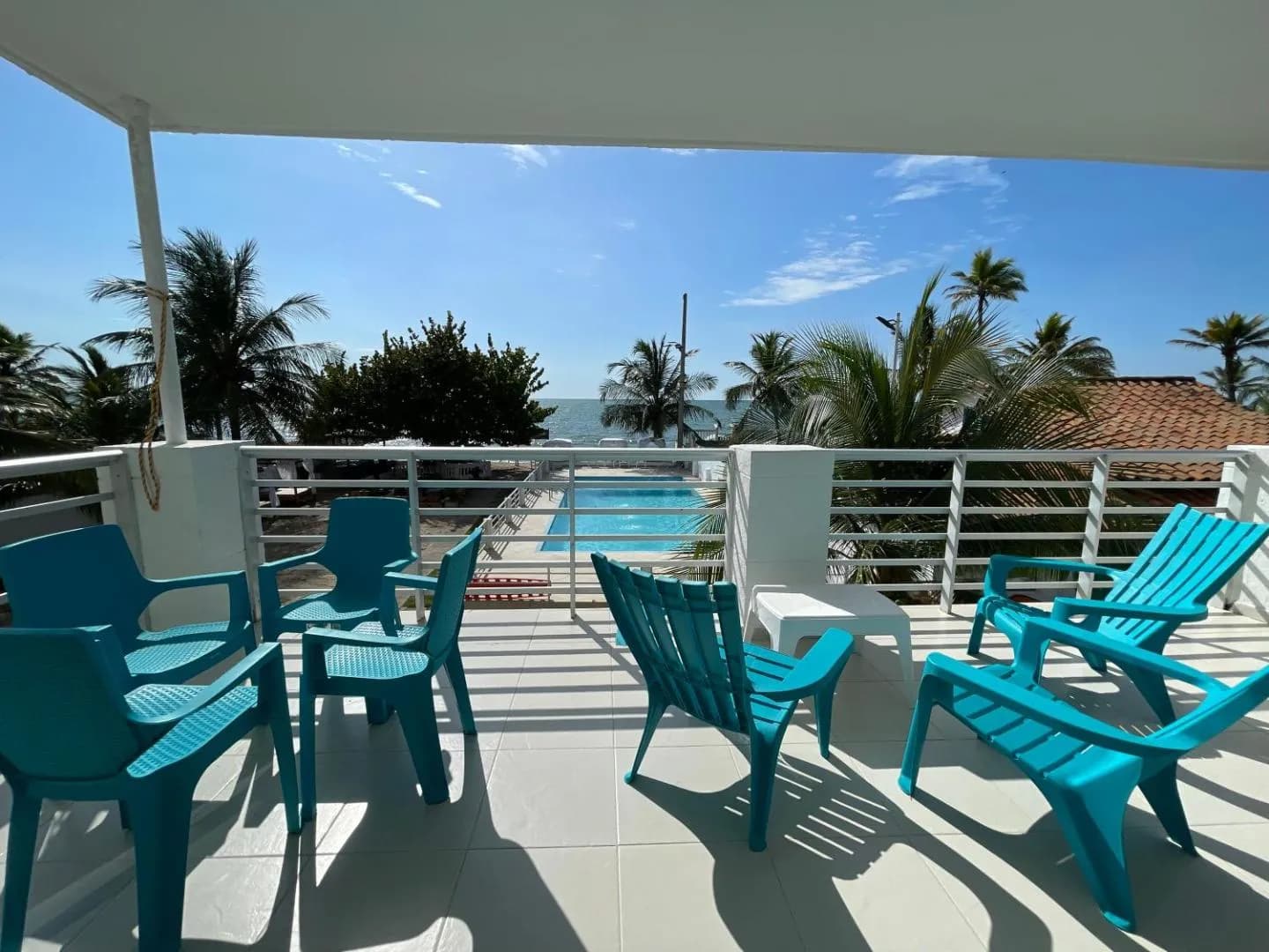 Terraza privada de Torre Blanca con sillas turquesa y vista a la piscina y el mar